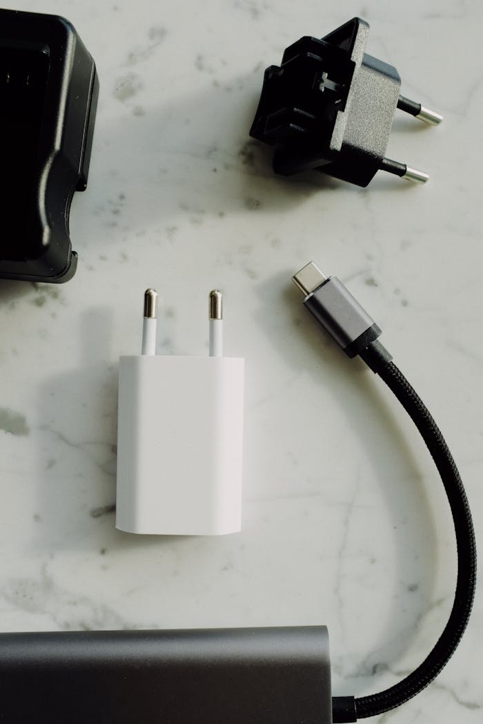 A collection of electrical plugs and a USB-C charger on a marble tabletop. Perfect for tech and electronics themes.